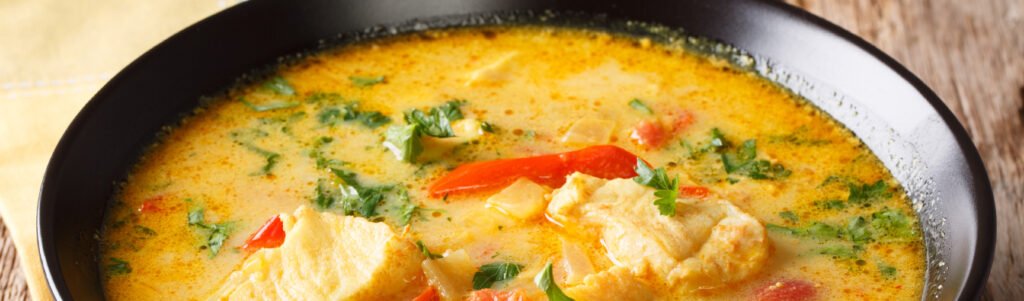 Moqueca capixaba servida com taça de vinho branco ao lado